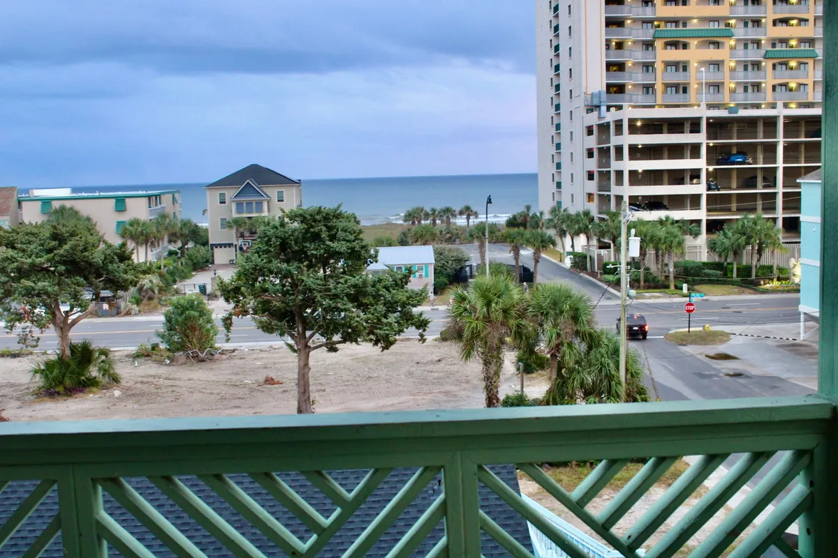 The hero image showcases a breathtaking ocean view framed by swaying palm trees, with tall buildings lining the shore. The scene invites guests to relax on the balcony, soak in vibrant sunsets, and enjoy the tranquil atmosphere by the beach.